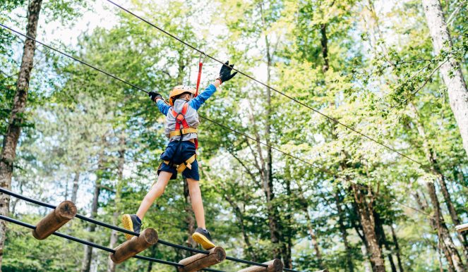 Boy walking on the agility bridge holding on to the ropes. High quality photo