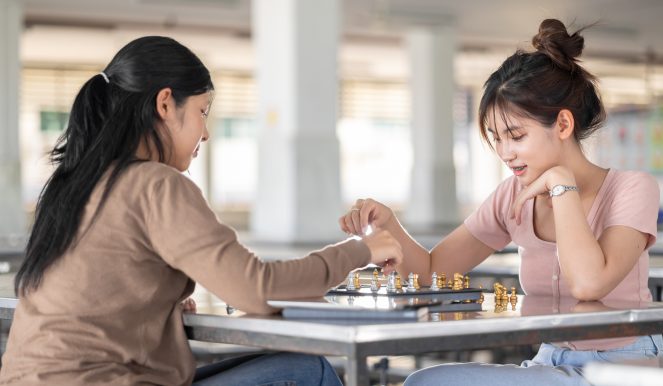 Smart students teen girl playing chess board game with friend at school campus leisure activity